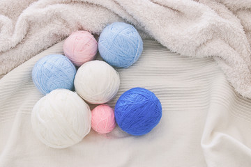 Fototapeta na wymiar pink' blue and white warm and cozy yarn balls of wool over soft bed.