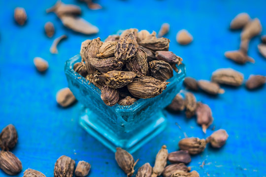 Raw black cardamom on a brownish wooden surface.