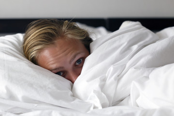 Morning time. Young beautiful and happy woman lies in bed.