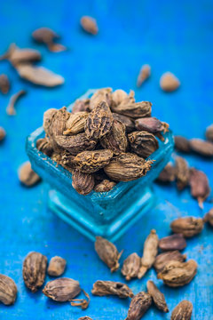 Raw black cardamom on a brownish wooden surface.