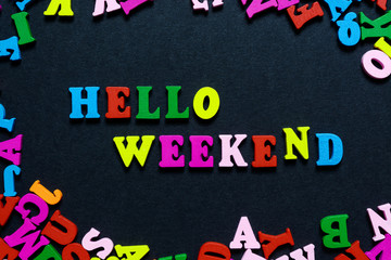 concept design - the word HELLO WEEKEND from multi-colored wooden letters on a black background, creative idea