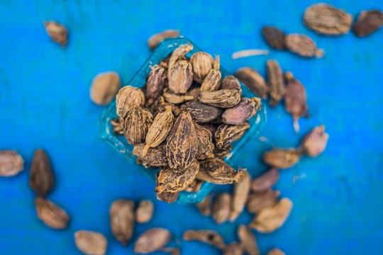 Raw black cardamom on a brownish wooden surface.