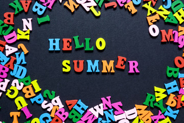 concept design - the word HELLO on SUMMER from multi-colored wooden letters on a black background, creative idea