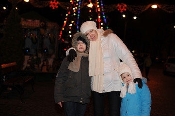 After celebrating the new year, a woman with children walks around the night city near the Christmas tree