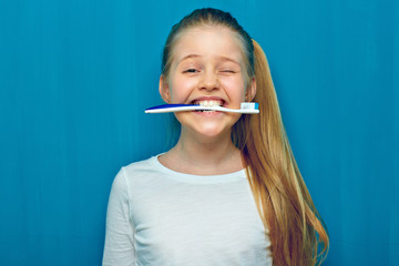 Little girl holding toothy brush with teeth.