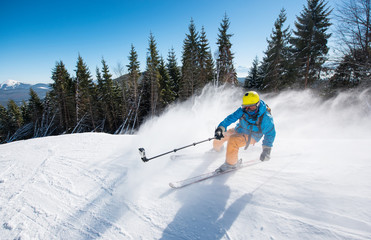 Action shot of professional skier taking selfies photo with a camera on selfie stick while skiing...