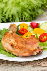 Spicy grilled chicken thigh and vegetables on a white plate.