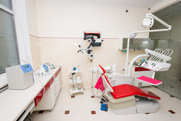 Denatal chair and modern dental equipment in red and white dental clinic room