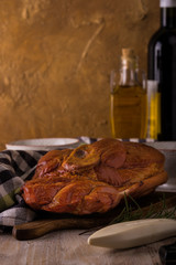 Smoked pork meat on cutting board with kitchen utensils and bottles