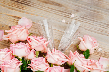 Pink blooming fresh valentines day rose flowers on wood with pair of champagne glasses
