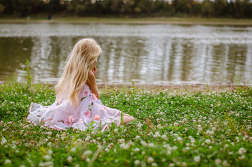 little lonely girl sitting in the grass by the river © katarinagondova