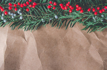 Christmas winter background green branches ,berries and brown wrinkled paper 