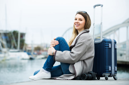 woman with luggage  posing at quay and smiling