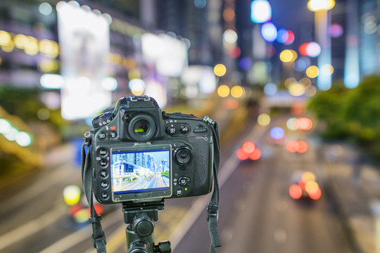 Photographing cityscape and traffic at night time. Camera in foreground