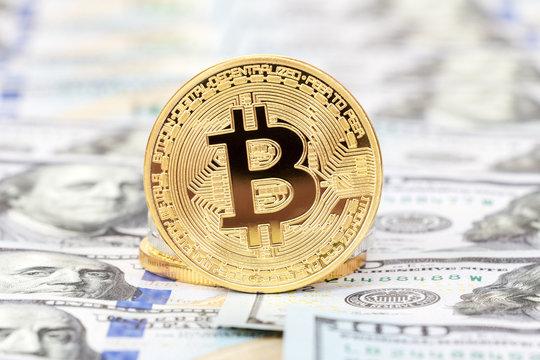 Golden bitcoin on the background of one hundred american dollars close up. Business concept of worldwide cryptocurrency