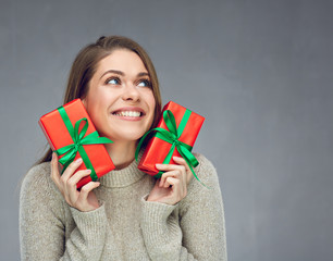 Happy woman wearing sweater holding two red gift boxes.