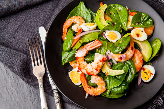 Fresh, healthy salad with shrimps, spinach and avocado on a black background. Top view
