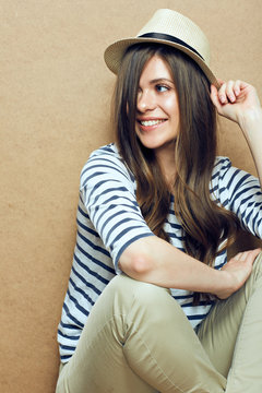 Sitting woman wearing striped shirt and hipster hat.