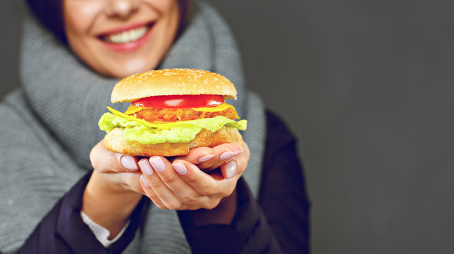 Smiling woman holding burger in two hands.