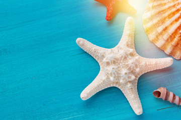 Summer corner border of sea shells scallop and star fish on blue wooden background
