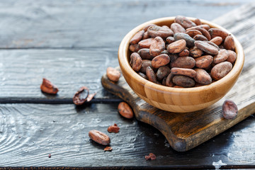Сocoa beans in wooden bowl closeup.