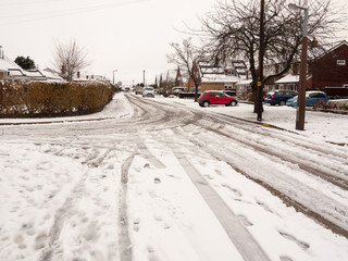 snow covered street road with tire tracks leading through village houses