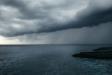 Dark blue sea storm, huge clouds and breakwaters.