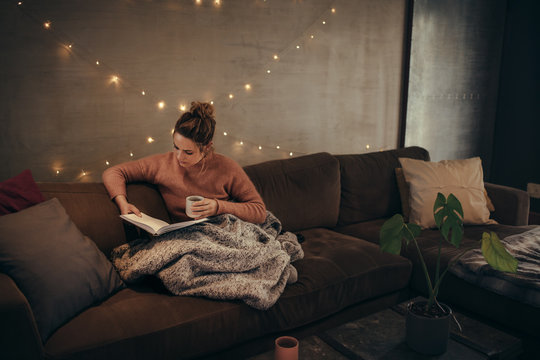 Woman reading book in cozy living room