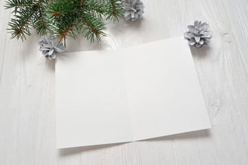 Mockup Christmas greeting card with tree branch, flatlay on a white wooden background, with place for your text