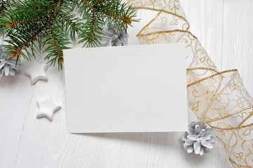 Mockup Christmas greeting card with tree and gold gift ribbon, flatlay on a white wooden background, with place for your text