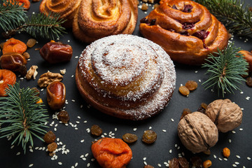 Buns with powdered sugar and crumb of coconut on a New Year's background. Beautiful pastry roll with nuts and dried fruits, Christmas dessert