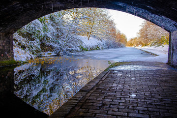 View of frozen Birmingham Canal under a bridge
