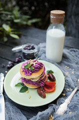 rustic composition: pancakes with berries cheese cream with dried apricots and a bottle of milk on a wooden table