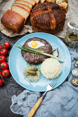 rustic composition: grilled meat with quail egg, mashed potatoes on a blue plate