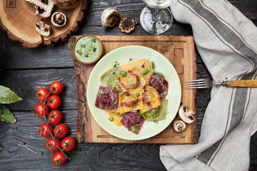 rustic composition: colorful ravioli with mushrooms on a wooden table with a glass of white wine - 184476596