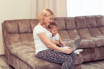 Happy pregnant mother with her kid boy using laptop at home in the living room