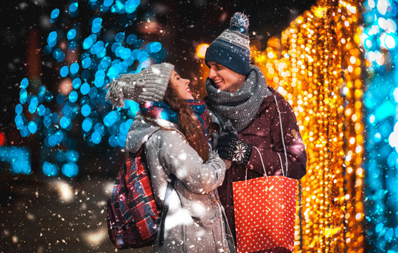 Couple With Gift Bag On Christmas Lights Background, Walking In The City At Evening