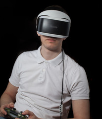 young man plays computer game using VR-helmet and joystick.