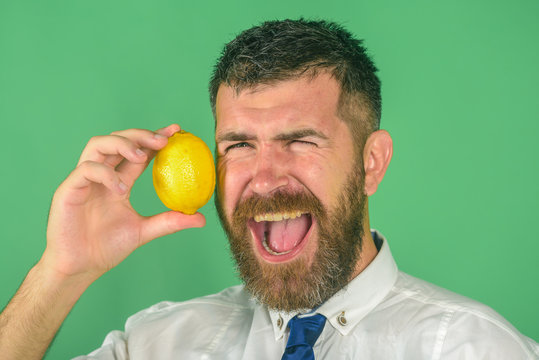 happy man with beard eat lemon fruit on green background