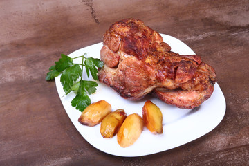 Juicy pork neck chops are grilled with potatoes on a white plate.