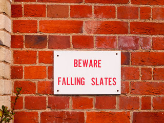 information sign on red brick wall beware falling slates