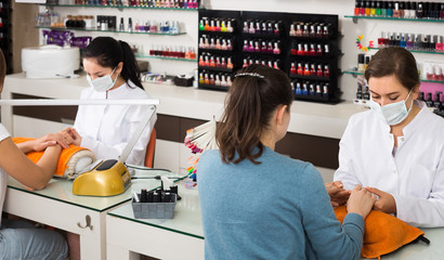 professional nail technicians performing manicure procedure in beauty salon