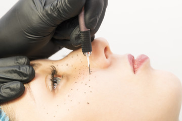 Permanent microblasting tattooing freckles to a woman in a beauty salon