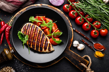 Grilled chicken fillet on black background, top view