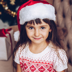 Christmas little girl in Santa Claus hat portrait indoors