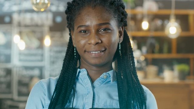 Beautiful African-American Cafe Owner Walking into Focus while in the Background Her Stylish Coffee House Shines with Lights. Shot on RED EPIC-W 8K Helium Cinema Camera.