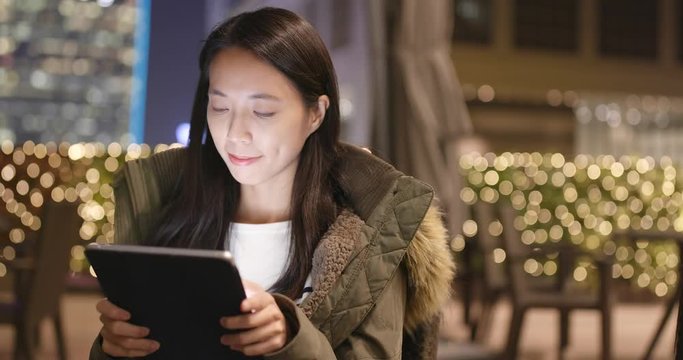 Woman look at tablet computer in coffee shop at night