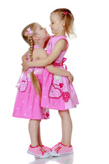 Two little girls hug.