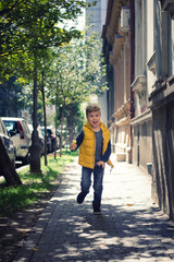 Fototapeta na wymiar Little boy having fun while running on a sidewalk.