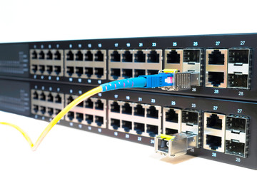 Two managed stackable Gigabit Ethernet switches with a connected optical wires are  on a white background.